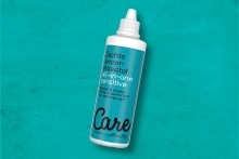 Fles Care alles-in-één lenzenvloeistof voor gevoelige ogen op een turquoise achtergrond.