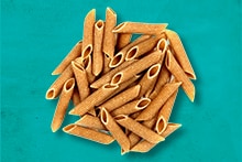 Volkoren penne pasta tegen een turquoise achtergrond