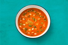 Kom met groentesoep op blauw oppervlak