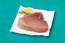 Tonijnfilet op een vel bakpapier met een schijfje citroen en dille.