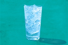 Glas met ijsblokjes voor een groene achtergrond