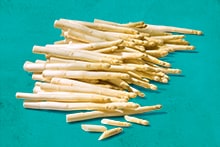 Een stapel verse witte asperges op een turquoise achtergrond