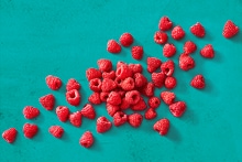 Verse frambozen verspreid op een turquoise ondergrond