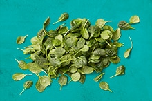 Verse spinazieblaadjes verspreid op een blauwe achtergrond