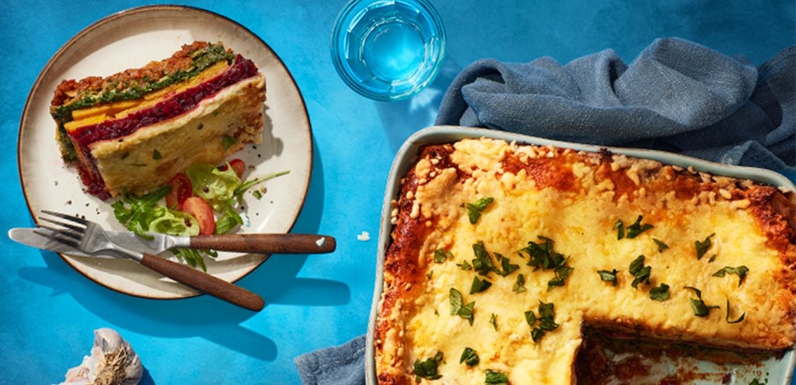 Lasagne in een ovenschaal en een stuk op een bord met bestek.