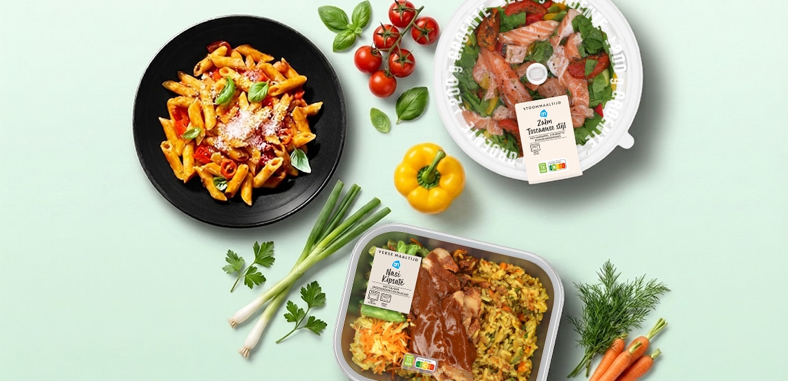 Bovenaanzicht van drie maaltijden: een bord pasta, een ronde schaal met zalm en een maaltijd met rijst, met daaromheen verse groenten en kruiden op een lichtgroene achtergrond.