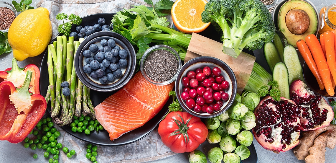 Assortiment van verse groenten en fruit, zalmfilet, en superfoods op een tafel