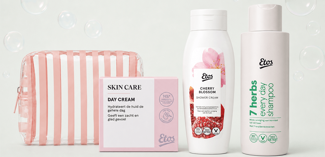 Verzorgingsset bestaande uit een transparant tasje met roze strepen, Etos Skin Care dagcrème, Etos Cherry Blossom douchecrème en Etos 7 Herbs Every Day shampoo.
