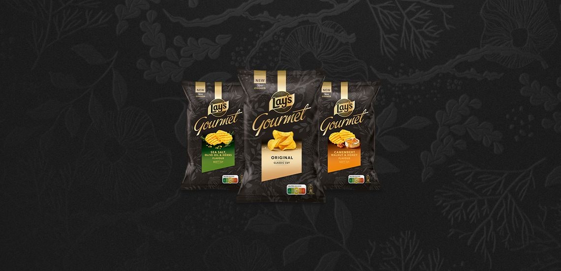 Drie zakken Lay’s Gourmet chips in de smaken Sea Salt, Original en Camembert Walnut Honey op een donkere achtergrond.