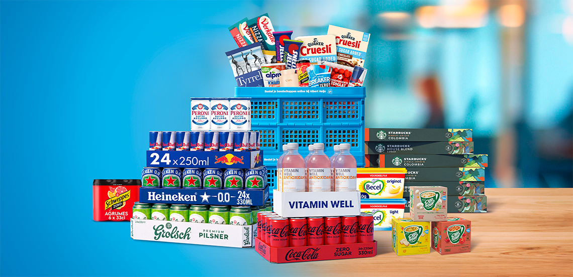 Stapel met A-merk producten zoals Grolsch, Heineken, Coca-Cola, Schweppes, Peroni, Red Bull, Starbucks, Quaker, Alpro, Becel en Cup-a-Soup naast een blauwe boodschappenkrat op een houten tafel, met een blauwe achtergrond.