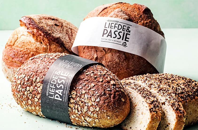 Verschillende broden uit de Liefde & Passie lijn van Albert Heijn, waaronder een meergranenbrood en een witbrood, met enkele sneetjes brood op de voorgrond.