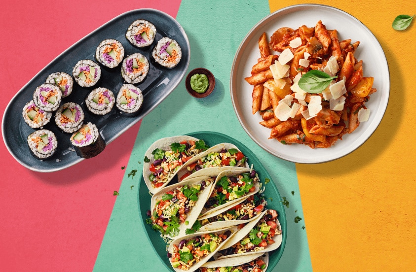 Assortiment van wereldkeuken gerechten met sushi, pasta en gevulde taco’s op kleurrijke achtergrond