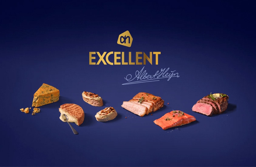 Verschillende luxe Albert Heijn Excellent producten, zoals kaas, vlees en vis, gepresenteerd op een blauwe achtergrond met het Excellent-logo.
