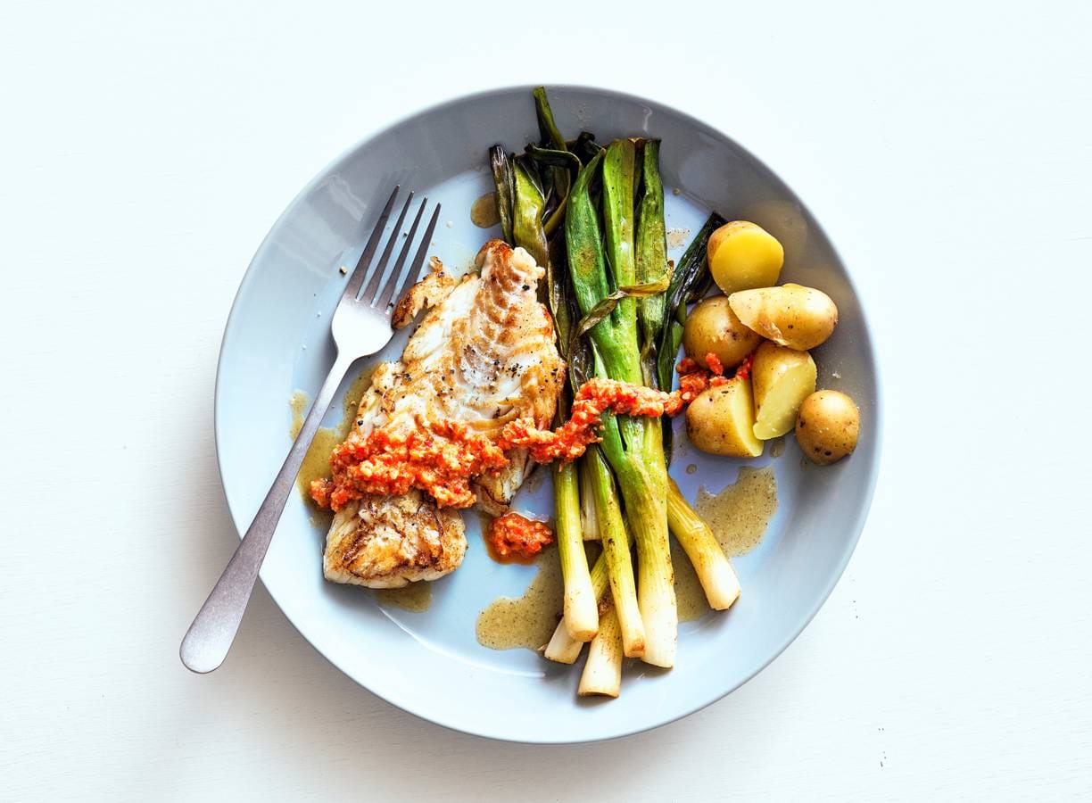 Gestoofde salade-ui met romesco en gebakken kabeljauw