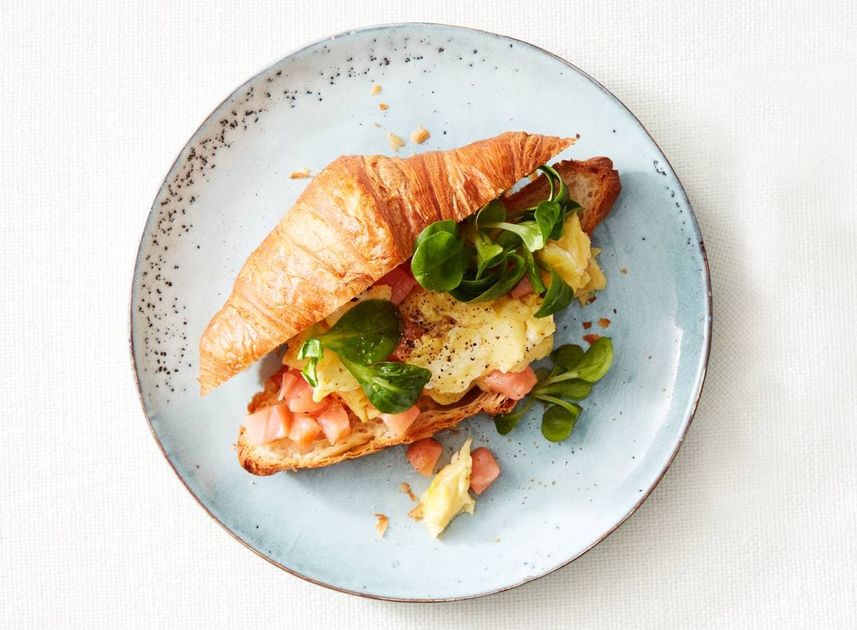 Croissant gevuld met roerei, gerookte zalm en veldsla