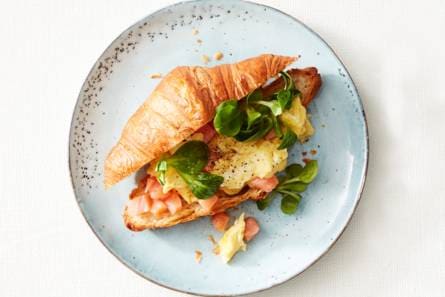 Croissant gevuld met roerei, gerookte zalm en veldsla