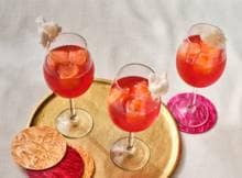 Niet vies van wat bling? Het is meteen feest met deze Aperol spritz met cranberry, glitterijsblokjes en suikerspin.