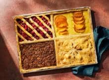Vier smaken in één plaattaart! Met pecan, cranberry, kaki en appel voor wie niet kan kiezen. Zo neem je toch gewoon een beetje van alles van deze zoete traybake.
