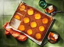 Kaki's maken deze upside-downcake niet alleen lekkerder, maar ook een stuk mooier. Combineer met slagroom, kaneel en kardemom voor de ultieme herfst-traybake.