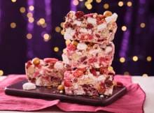Witte chocolade vol crunchy koekjes, zoute sticks, gevriesdroogd fruit en pareltjes die samen opstijven tot een feestelijke rocky road met knapperige verrassingen en kleurrijke toppings.